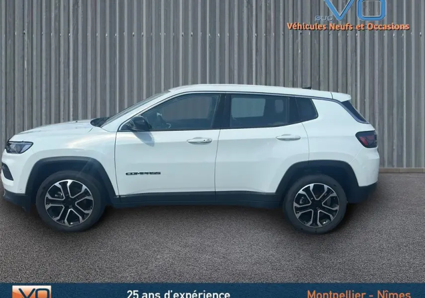 Vue latérale droite du Jeep Compass blanc 2024 avec jantes 17 pouces et roue de secours visible sur fond industriel.