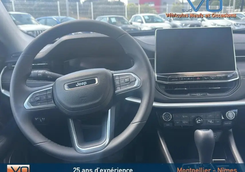Intérieur du Jeep Compass 2024 montrant le volant et l'écran tactile central, avec commandes au volant visibles.