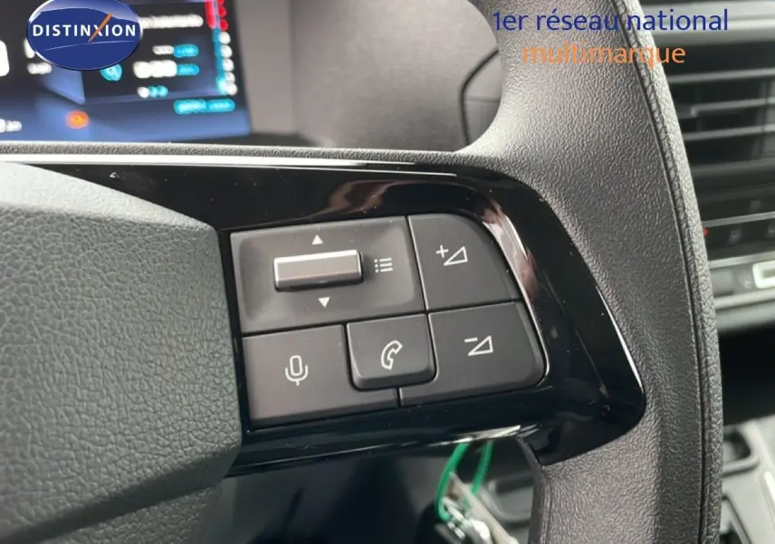 Gros plan sur les commandes au volant noir du Citroën Jumpy gris Artense, avec écran digital en arrière-plan.