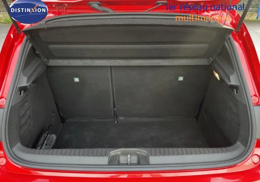 Coffre ouvert vu de l'arrière d'une Renault Clio rouge Désir Métal, montrant un espace de rangement vide et propre.