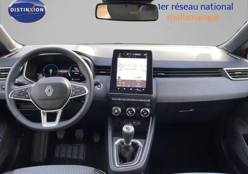 Vue intérieure avant de la Renault Clio rouge Désir Métal 2025, avec tableau de bord numérique et boîte manuelle.