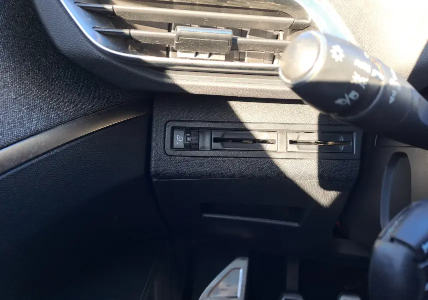 Détail du tableau de bord côté gauche avec commandes de réglage des phares et aérateurs noirs dans un Peugeot 5008 gris 2019.