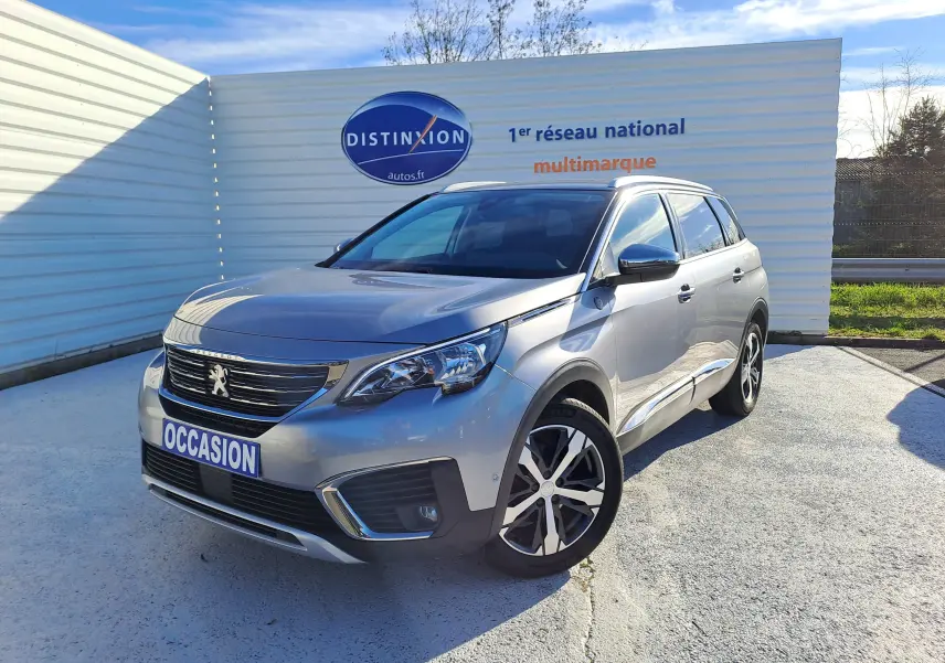Peugeot 5008 gris en 3/4 avant droit, SUV familial avec jantes alliage et calandre chromée visible en extérieur.