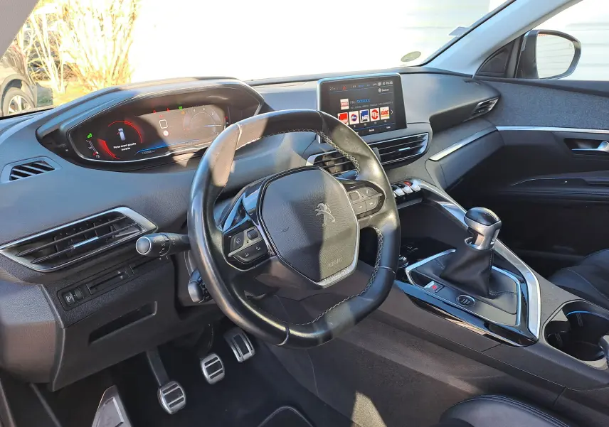 Vue intérieure côté conducteur du Peugeot 5008 gris de 2019, avec volant compact, tableau de bord numérique et levier de vitesses manuel.