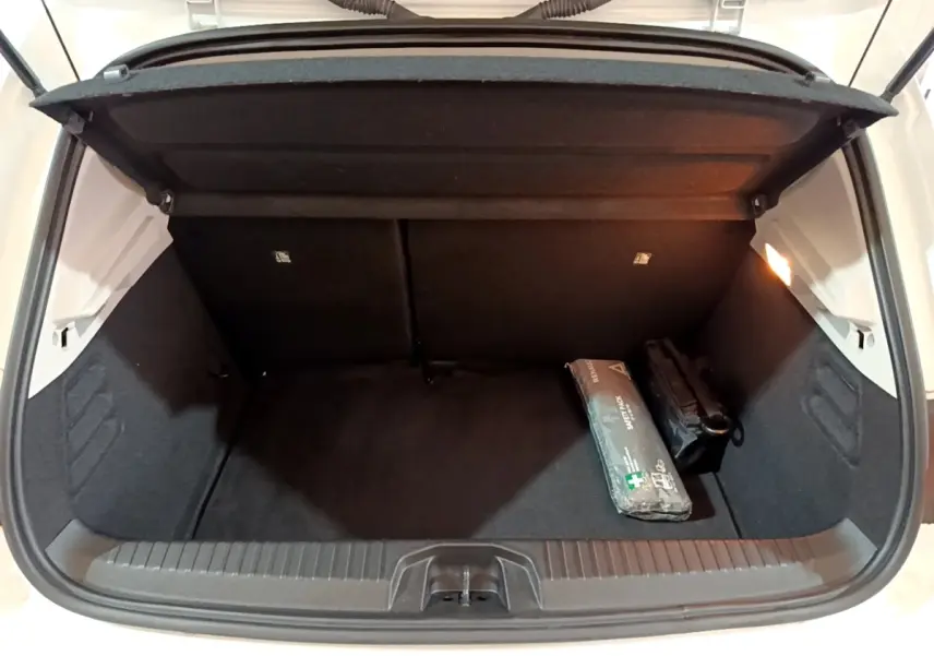 Coffre ouvert de la Renault Clio Business blanc, vue arrière, avec kit de secours et éclairage intérieur allumé.