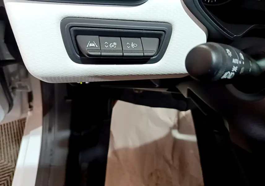 Gros plan sur les commandes d'assistance à la conduite sur tableau de bord blanc de la Renault Clio Business TCe 100 GPL 2023.