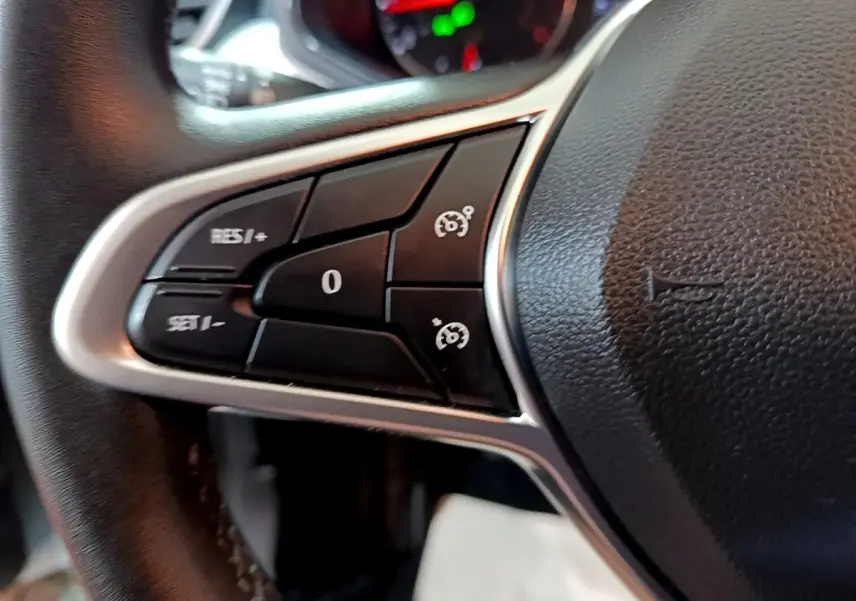 Gros plan sur les commandes de régulateur de vitesse au volant cuir noir de la Renault Clio Business blanc.