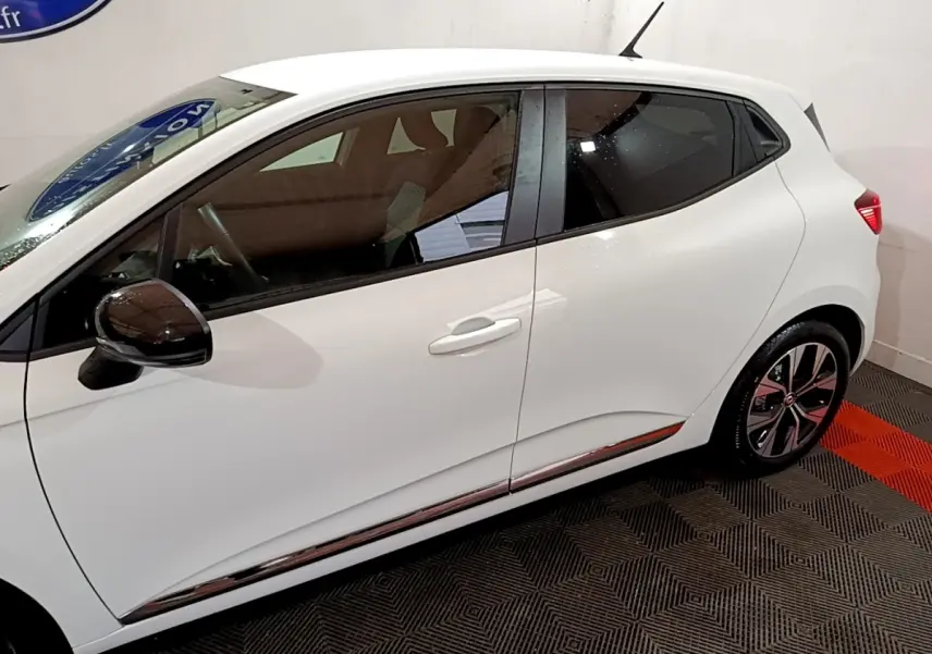 Profil droit d'une Renault Clio blanche 2023 avec rétroviseurs noirs et jantes alliage distinctives.