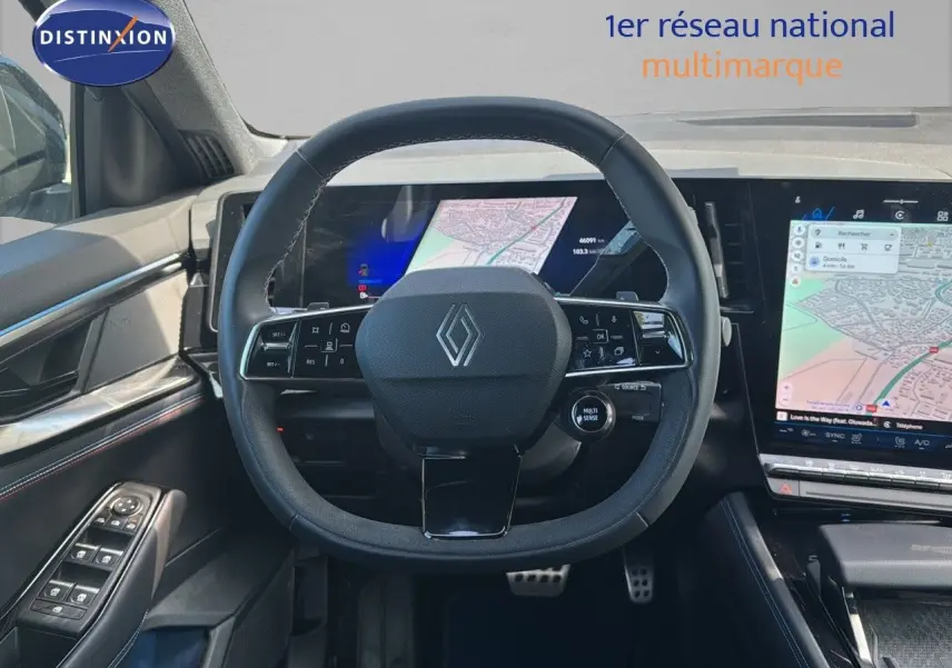Vue intérieure centrée sur le volant Renault avec tableau de bord numérique et écran tactile affichant une carte GPS.