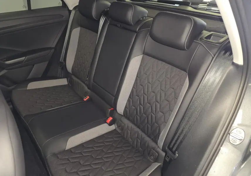Vue intérieure côté droit des sièges arrière gris et noir du Volkswagen T-Roc 2025 avec ceintures de sécurité visibles.