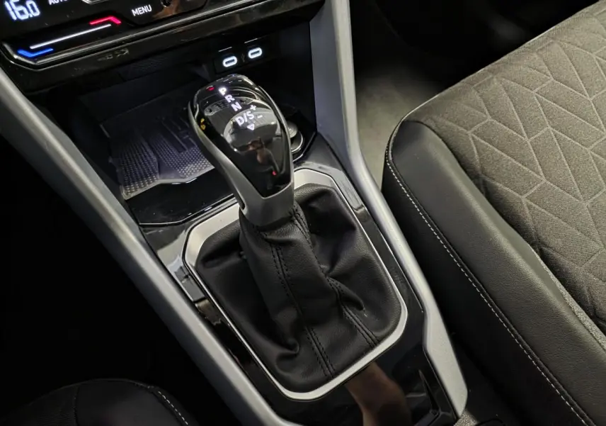 Gros plan sur la commande de boîte automatique et la console centrale du Volkswagen T-Roc 2025, sellerie tissu gris.