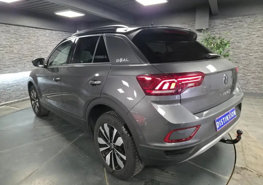 Volkswagen T-Roc gris en 3/4 arrière droit, toit noir avec logo GOAL et attelage démontable visible.