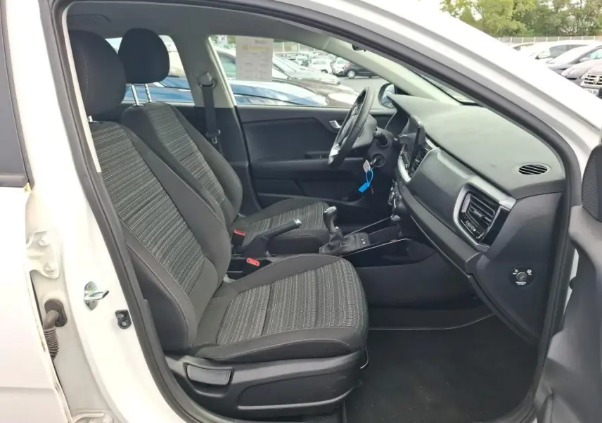 Vue intérieure côté conducteur du Kia Stonic blanc 2022, montrant les sièges avant et la console centrale avec boîte manuelle.