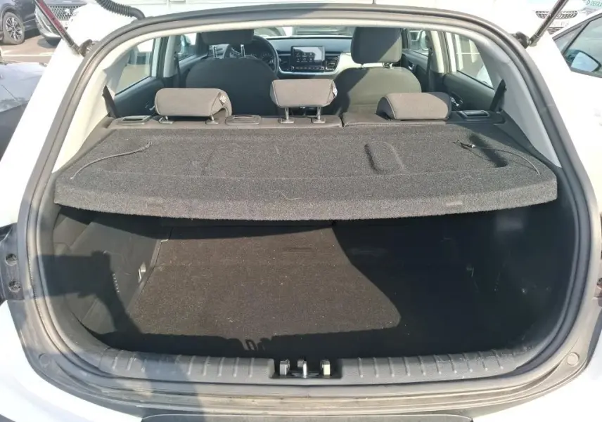 Coffre ouvert vu de l'arrière d'un KIA Stonic blanc 2022, avec cache-bagages en place et sièges arrière visibles.
