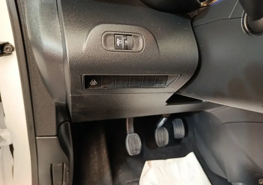Détail intérieur côté conducteur du Citroën Berlingo blanc 2020 montrant les pédales et commandes de réglage des phares.
