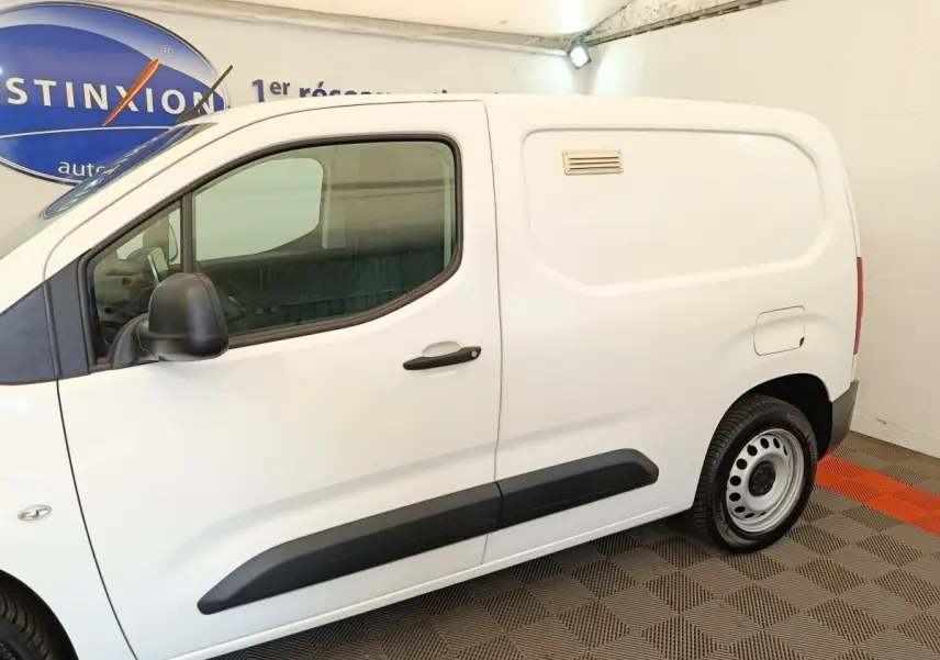 Vue de profil côté gauche d’un Citroën Berlingo blanc utilitaire avec porte latérale pleine et jantes acier.