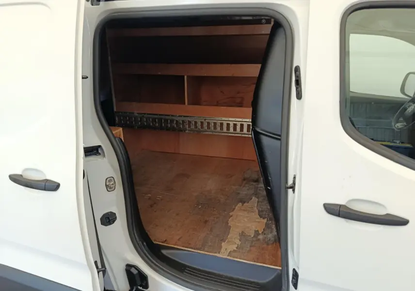 Vue latérale gauche sur la porte coulissante ouverte du Citroën Berlingo blanc, montrant l’espace de chargement en bois.