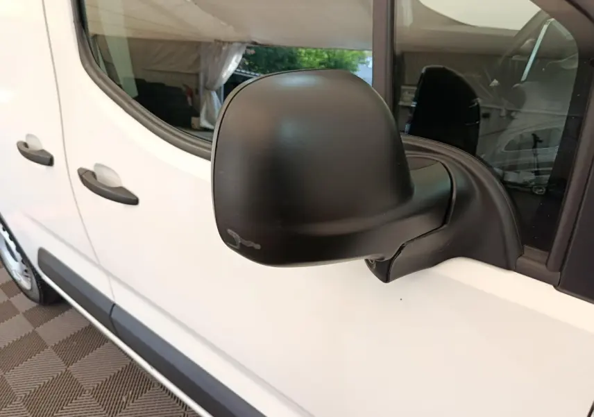 Rétroviseur noir en gros plan côté gauche d’un Citroën Berlingo blanc, vue partielle sur la porte avant.