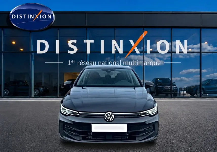Vue frontale d'une Volkswagen Golf 1.5 ETSI Evo2 noire garée devant une vitrine avec logo Distinxion.