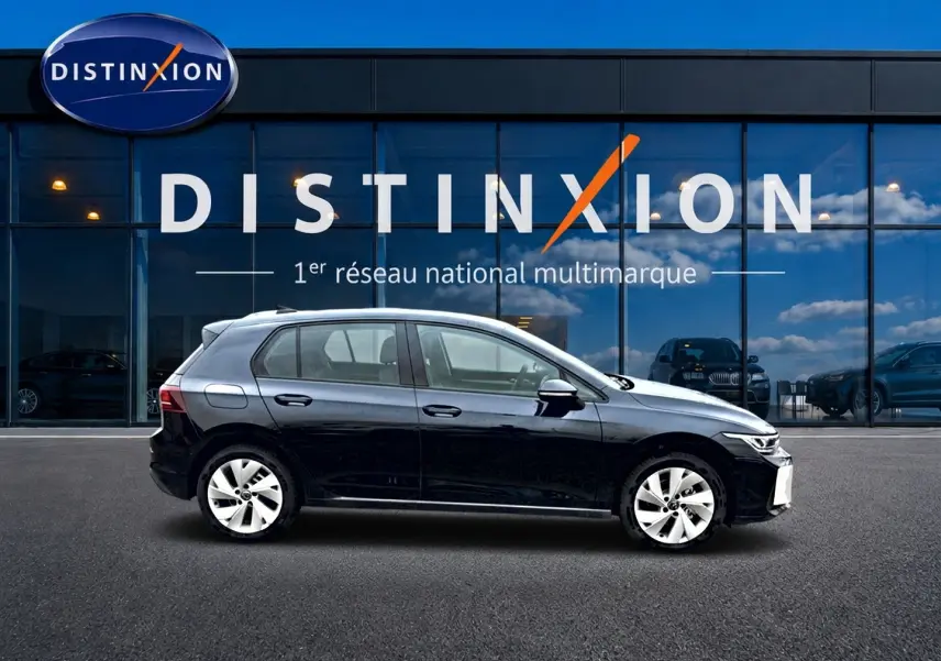 Profil côté gauche d'une Volkswagen Golf noire 2026 garée devant une vitrine avec logo Distinxion.