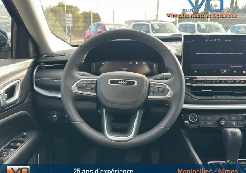 Vue frontale intérieure du volant Jeep Compass gris 2024 avec tableau de bord numérique et écran tactile central.