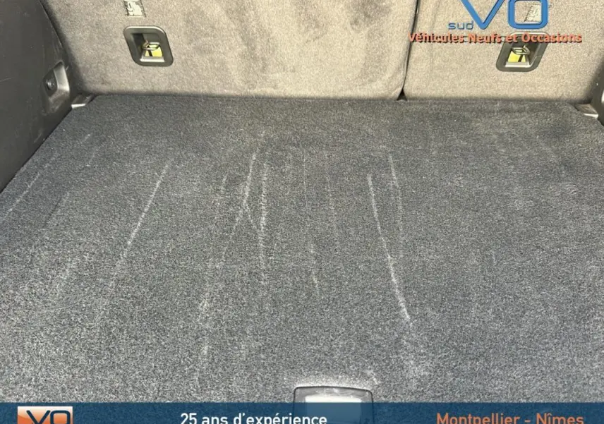 Vue du coffre spacieux et propre du Jeep Compass gris 2024, mettant en valeur la moquette et les fixations arrière.