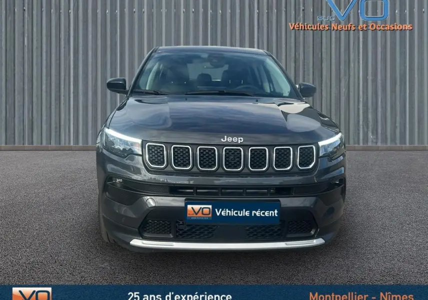 Vue frontale d'un Jeep Compass gris 2024 avec calandre à sept fentes et phares LED allumés.