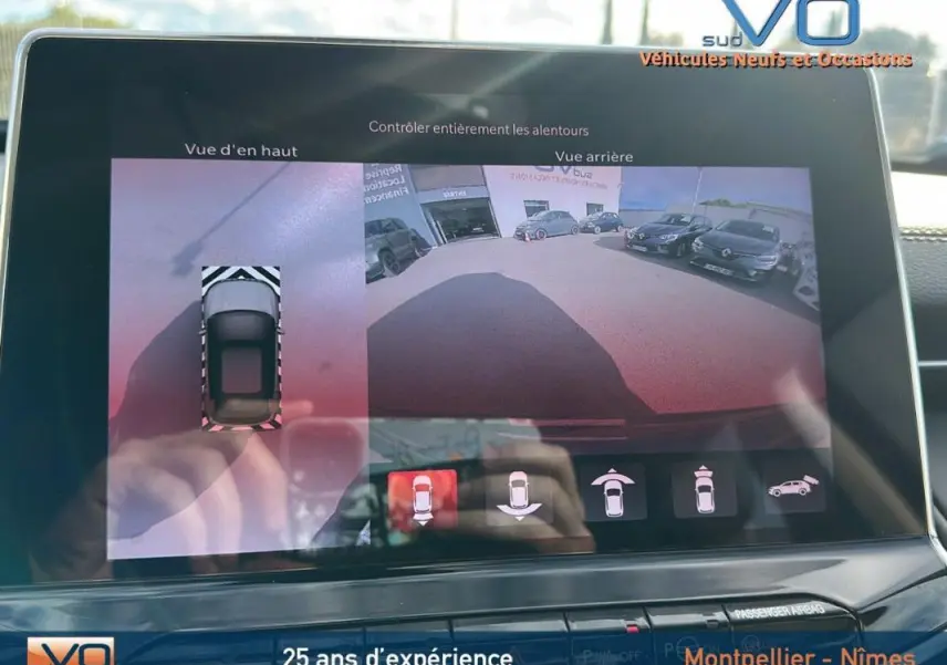 Écran tactile du Jeep Compass gris 2024 montrant la caméra de recul avec vue arrière et vue d’en haut du véhicule.