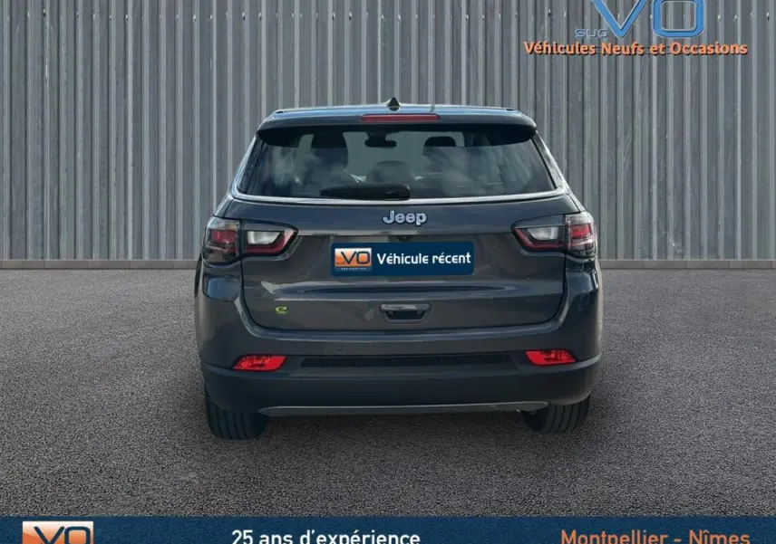 Vue arrière d'un Jeep Compass gris 2024 avec feux LED et logo Jeep bien visible sur un fond neutre.
