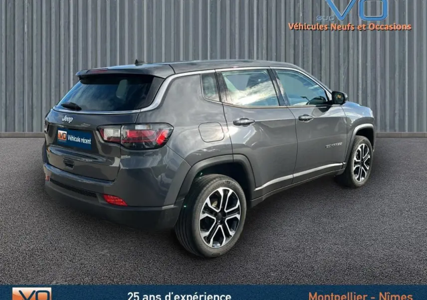 Jeep Compass gris vue 3/4 arrière droit, jantes alliage 18 pouces et feux arrière LED visibles.