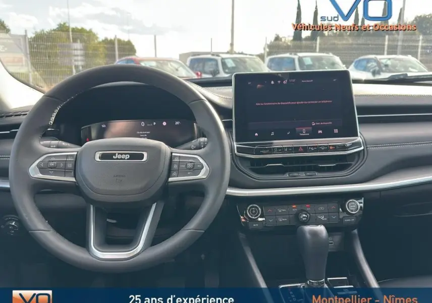 Vue intérieure du tableau de bord du Jeep Compass gris 2024 avec volant multifonction et écran tactile central.