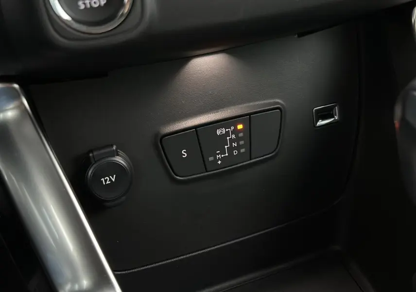 Gros plan sur la commande de boîte automatique et prise 12V dans l'habitacle noir du Citroën C3 Aircross 2024.