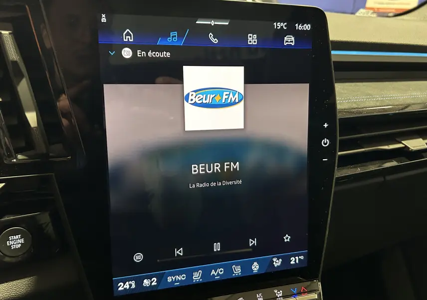 Écran tactile central du tableau de bord du Renault Austral blanc nacré satin, affichant la radio Beur FM.