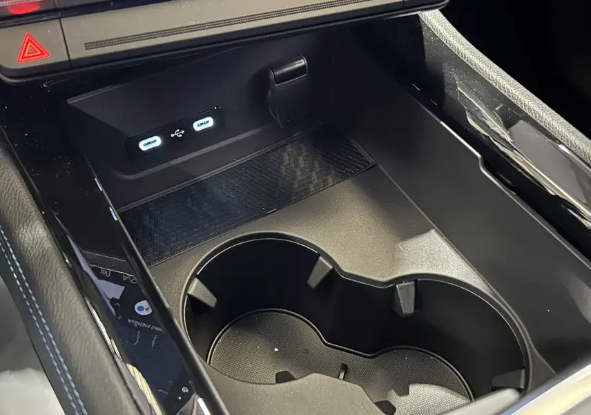 Gros plan sur la console centrale noire avec porte-gobelets et ports USB du Renault Austral blanc nacré satin.