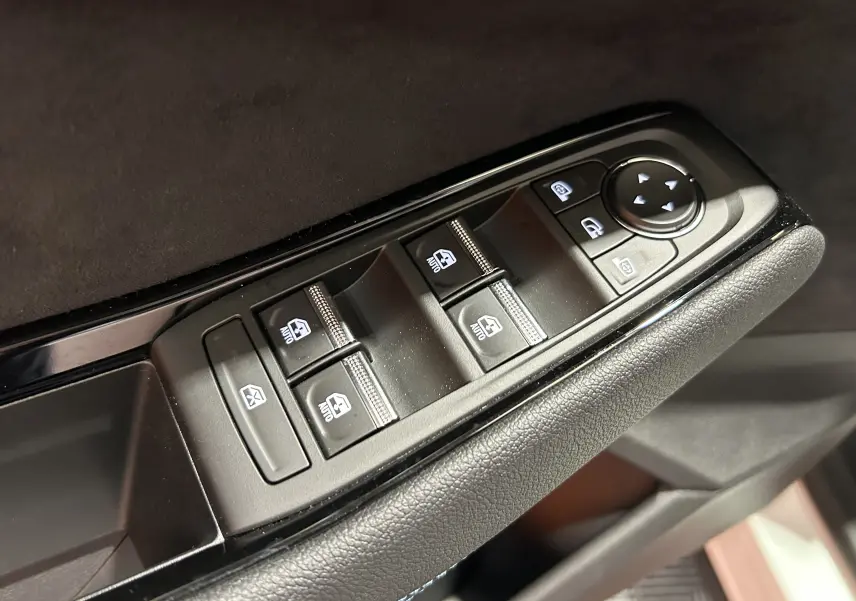 Gros plan sur les commandes de lève-vitres et rétroviseurs côté conducteur du Renault Austral blanc nacré satin.