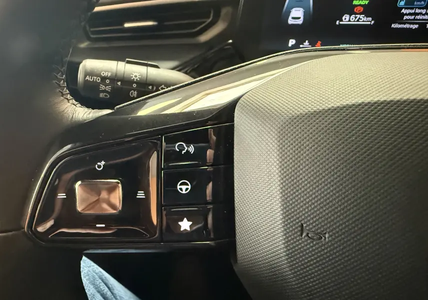 Gros plan sur les commandes au volant à gauche du MG3 1.5 L Hybrid+ 2025, avec tableau de bord numérique en arrière-plan.