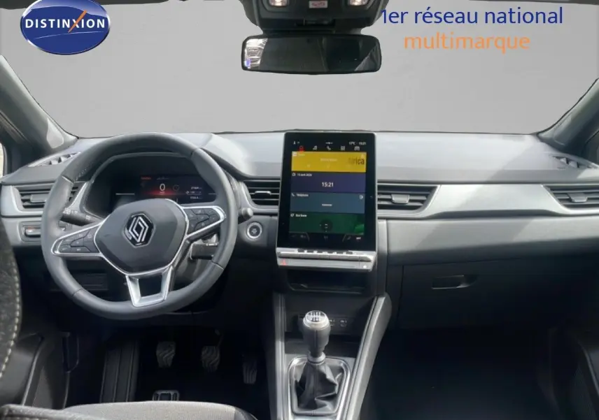 Vue intérieure avant du Renault Captur 2025, tableau de bord noir avec écran tactile vertical et levier de vitesse manuel.