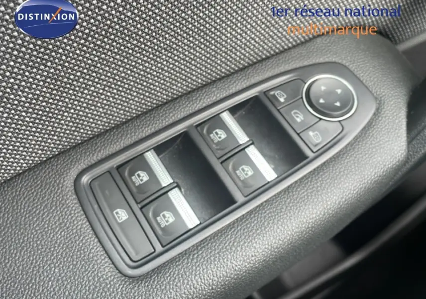 Gros plan sur les commandes des vitres électriques et rétroviseurs sur la porte côté conducteur d’un Renault Captur gris cassiopée métal avec toit noir.