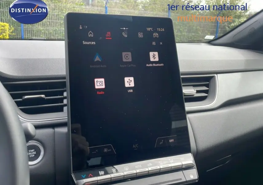 Vue intérieure centrée sur l'écran tactile vertical du tableau de bord du Renault Captur 2025, avec démarrage sans clé visible.