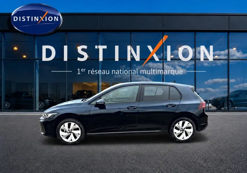 Vue de profil côté gauche d'une Volkswagen Golf noire 2026 garée devant une vitrine avec logo Distinxion.