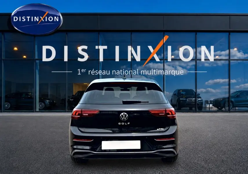 Vue arrière d'une Volkswagen Golf noire 2026 garée devant une vitrine avec logo Distinxion.