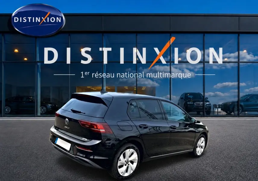 Vue 3/4 arrière droite d'une Volkswagen Golf noire 2026, avec jantes alu et vitres arrière surteintées devant un showroom Distinxion.