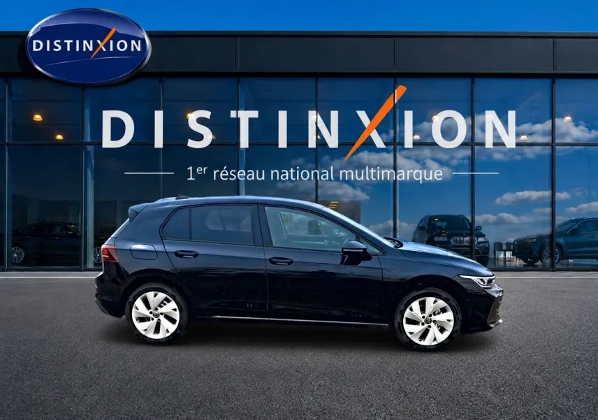 Vue de profil côté gauche d'une Volkswagen Golf noire 2026 garée devant une vitrine avec logo Distinxion.