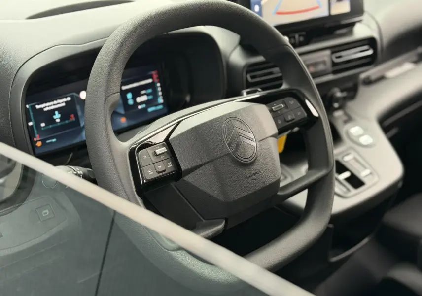 Vue rapprochée du volant multifonctions noir du Citroën Berlingo 2026 avec tableau de bord numérique et écran tactile.