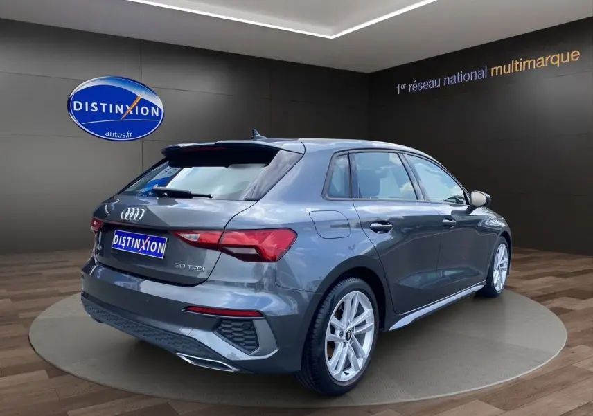 Audi A3 Sportback gris Daytona vue 3/4 arrière droit, mettant en valeur ses feux LED et jantes alliage.