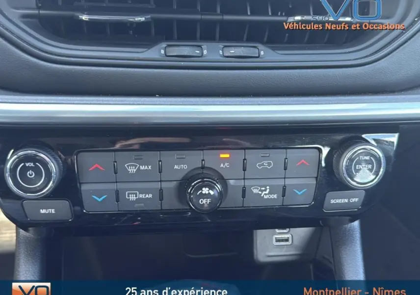 Panneau de climatisation et commandes centrales du Jeep Compass blanc 2024 avec écran tactile et prise USB visible.