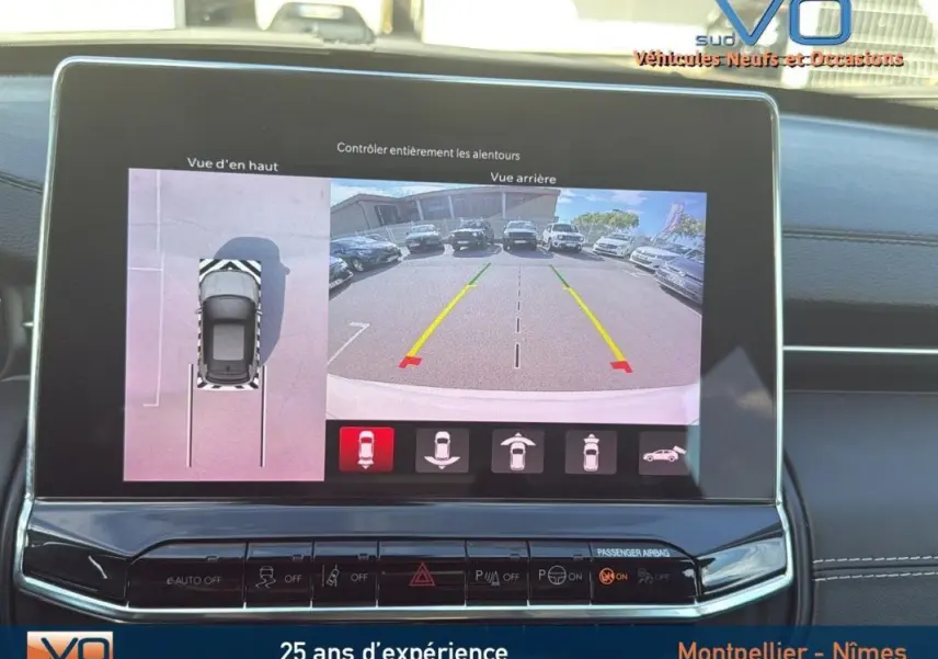 Écran tactile du Jeep Compass 2024 montrant la caméra de recul et la vue aérienne du véhicule blanc en stationnement.