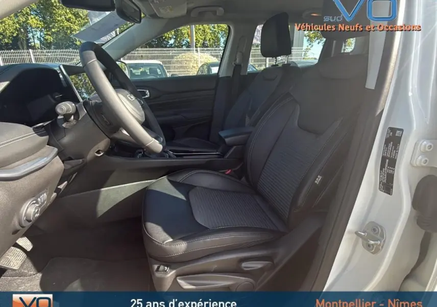 Intérieur avant droit du Jeep Compass blanc 2024, sièges noirs avec accoudoir central et tableau de bord moderne.