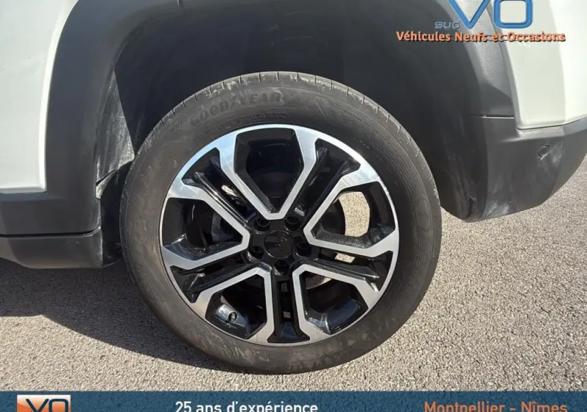 Gros plan sur la jante alliage 18 pouces noire et argent du côté avant droit d’un Jeep Compass blanc 2024.