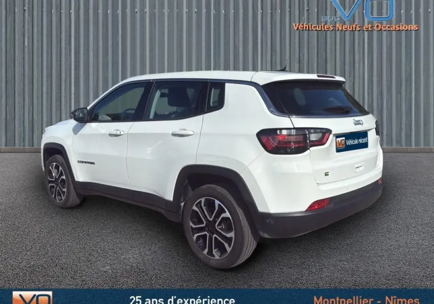 Jeep Compass blanc en vue 3/4 arrière droit, jantes alliage 18 pouces et logo e-Hybrid visible sur le hayon.